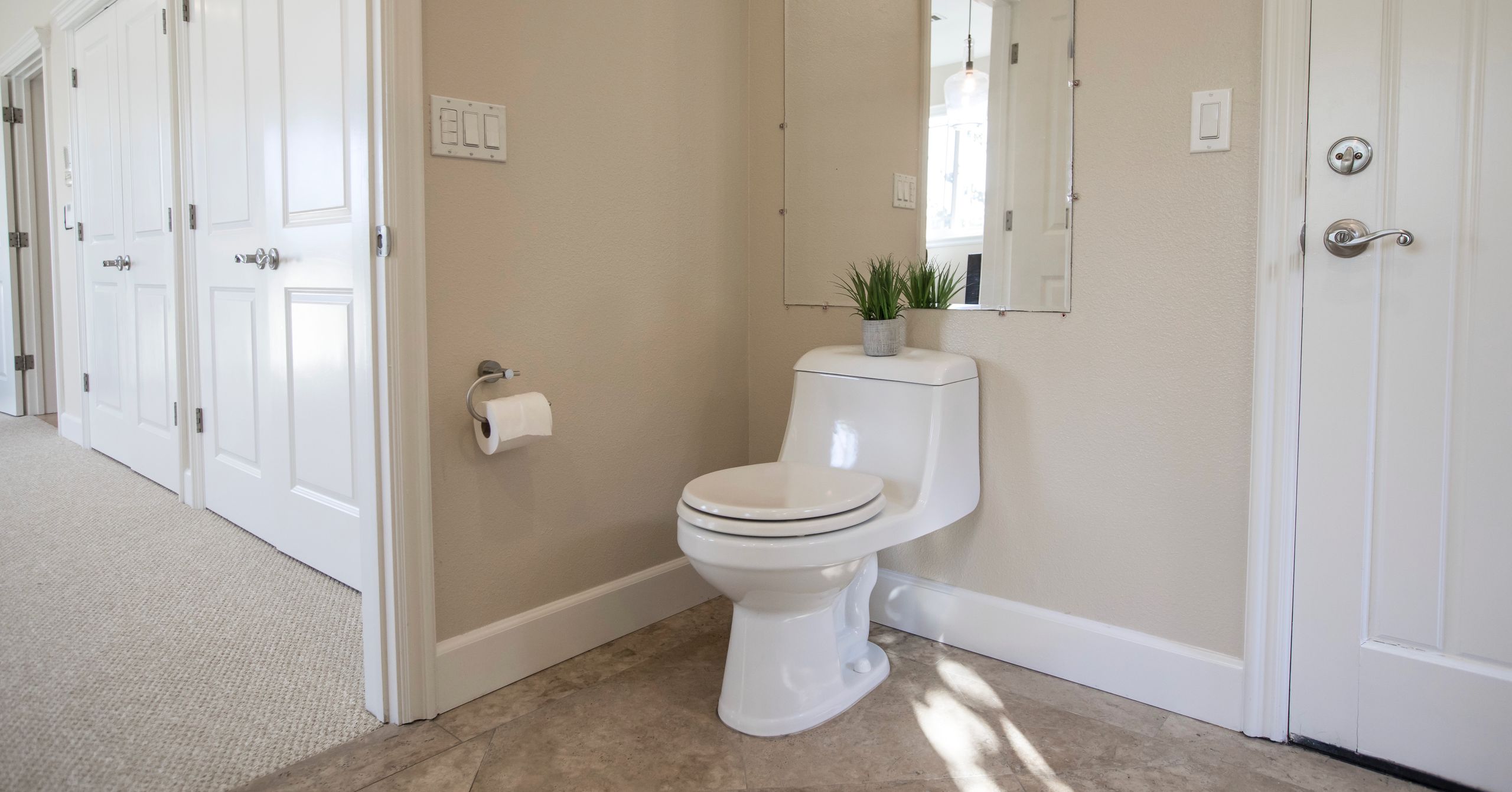 Contemporary bathroom design featuring a white toilet, mirror, and decor.